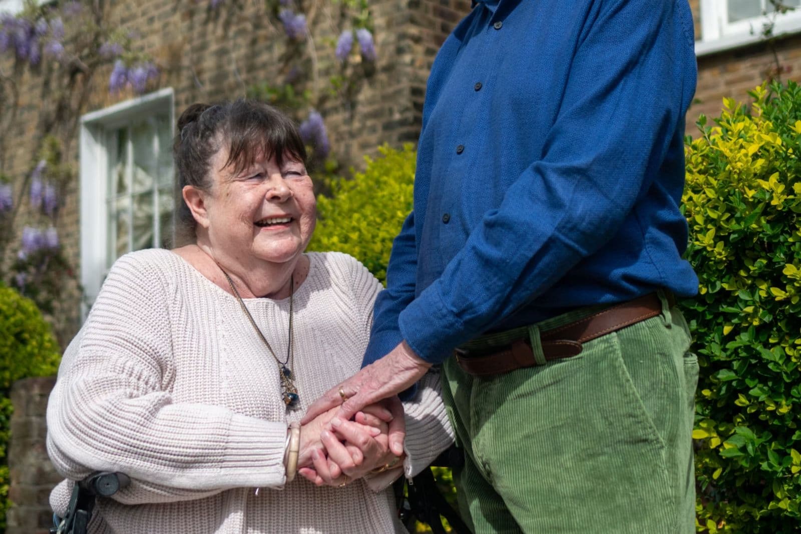 Two older adults enjoying a bright day together outside their home